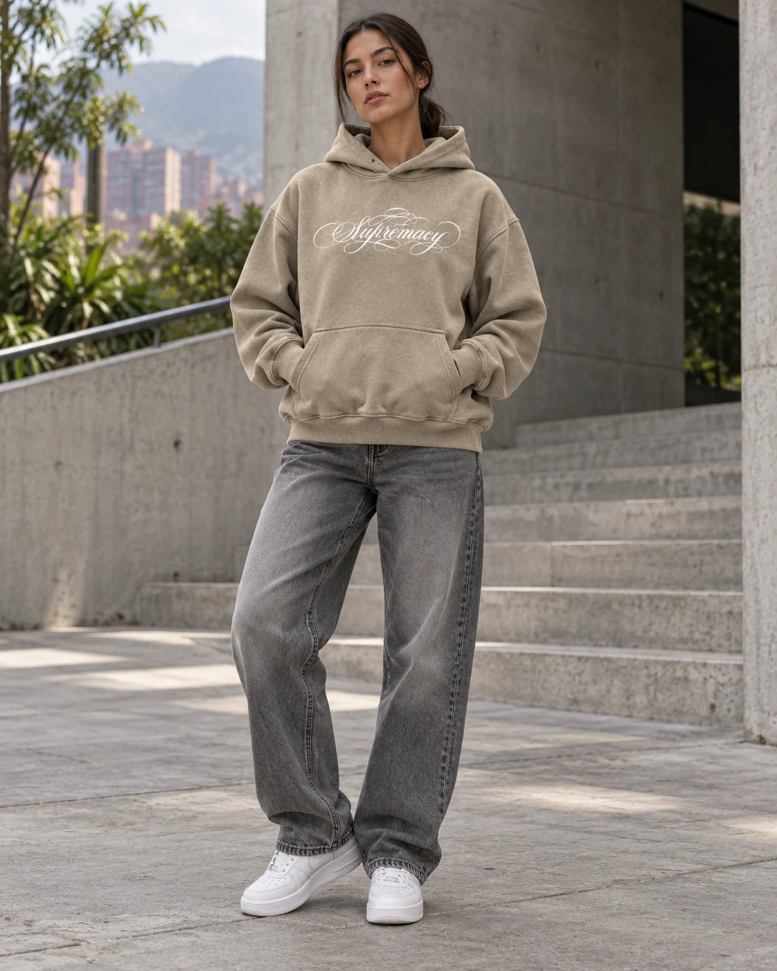 Modelo con hoodie OMATIC Boxy Fit beige, gráfica blanca al frente y jeans grises
